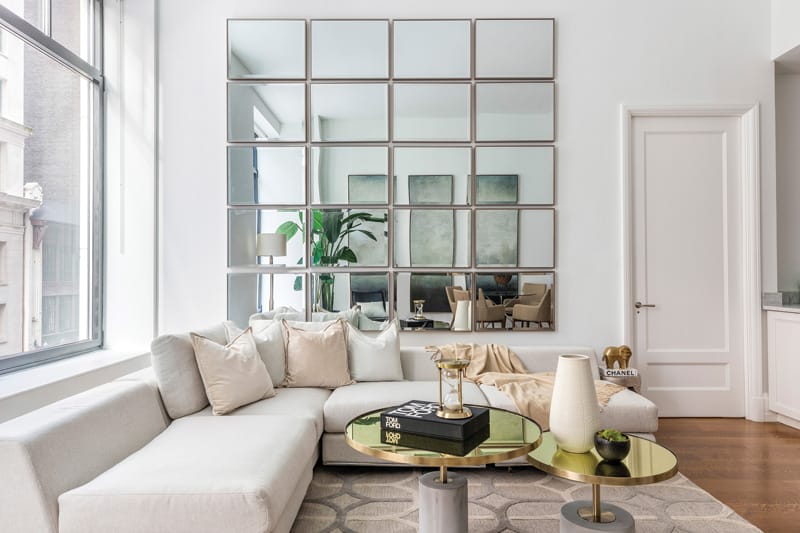 Identical rectangular mirrors hung in a grid pattern help add height to a loft-like living space | Photograph courtesy of Design Recipes