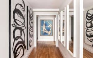 A series of mirrors placed across from artwork helps elongate a hallway. (Scott Morris/Design Recipes) Image