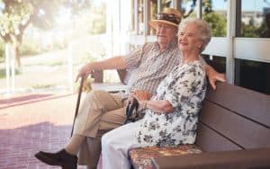 Retired couple sitting on a bench outside their home Image