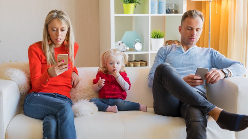 Young parents ignore their kid and looking at their mobile phones