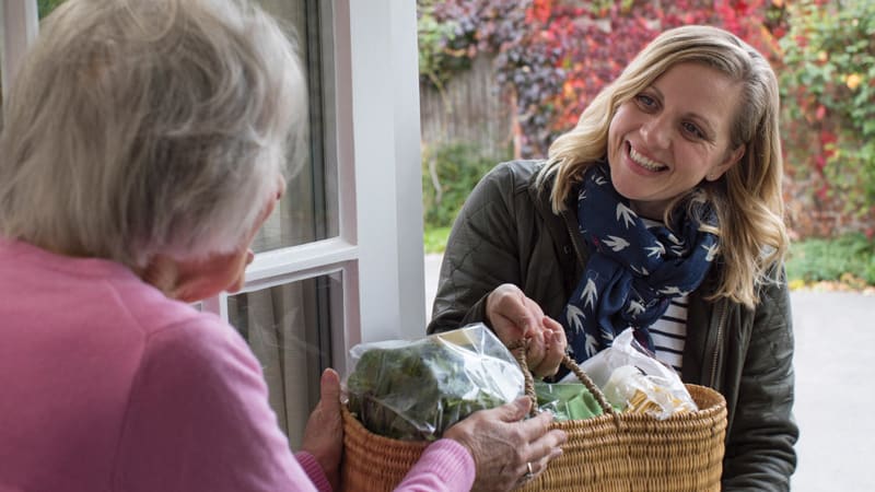 A woman volunteering with Naborforce brings an elderly local groceries