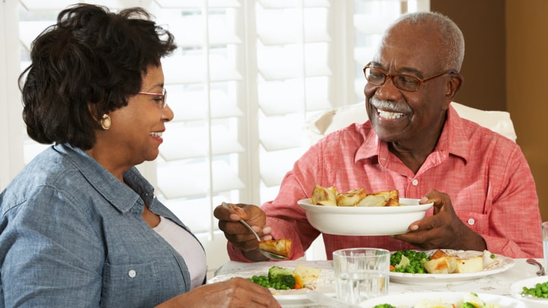 Married couple enjoying dinner at home together smiling