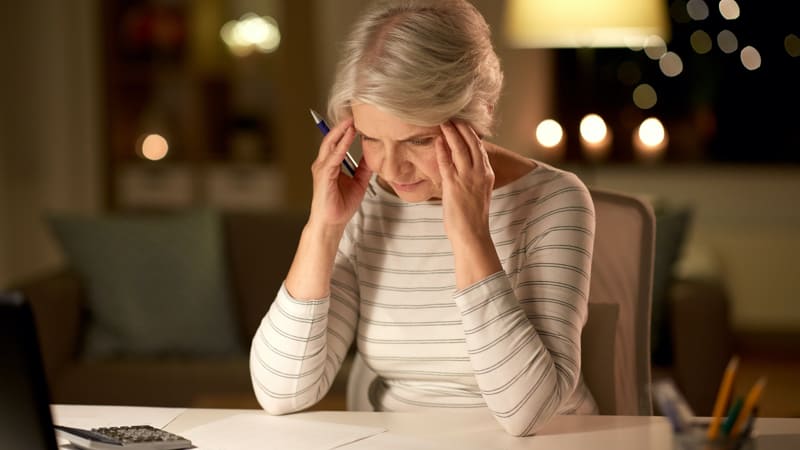 Stressed senior woman staring at service club papers and getting stressed