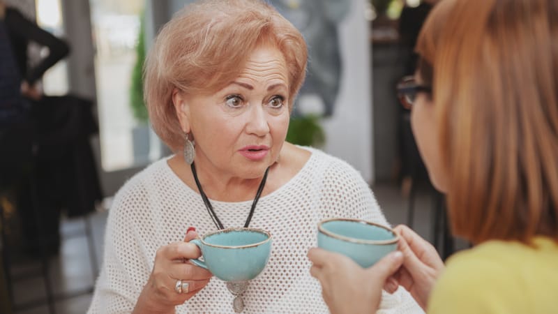 Two mature women drinking tea and gossiping