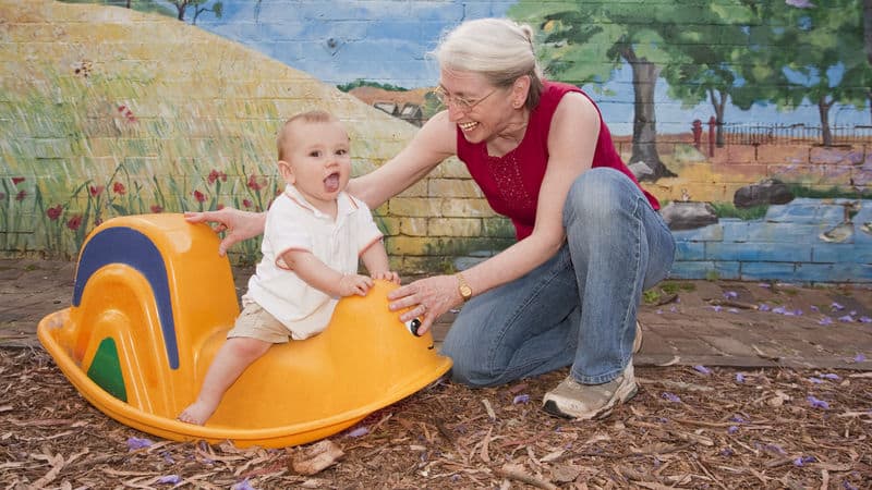 Grandma playing with her grandson in a toy rocking thing Image