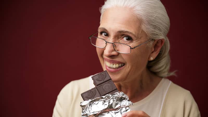 Senior woman loving herself some dark chocolate Image