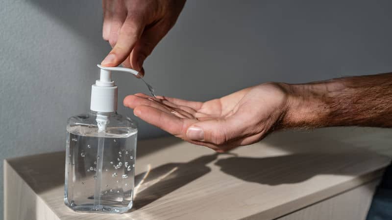 COVID-19: Man using hand sanitizer because he's so worried about it Image