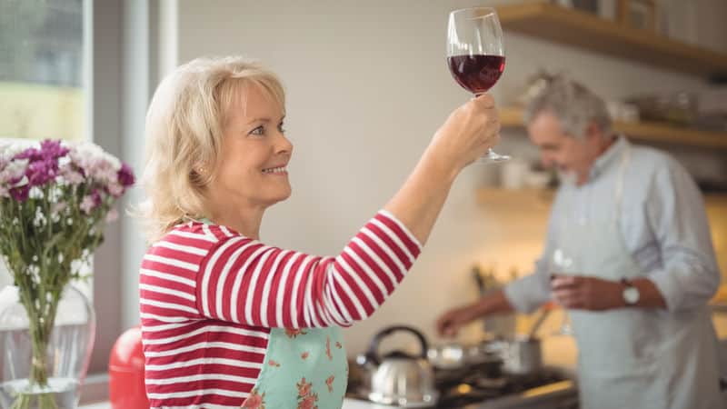 Man cooks dinner while alcoholic wife stares lovingly at her glass of wine Image