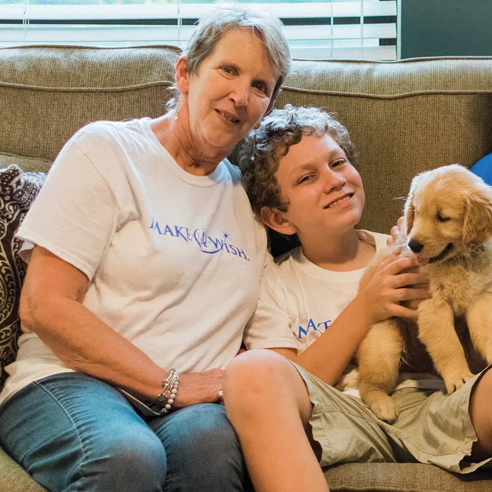 Make-a-Wish volunteer and child with a puppy