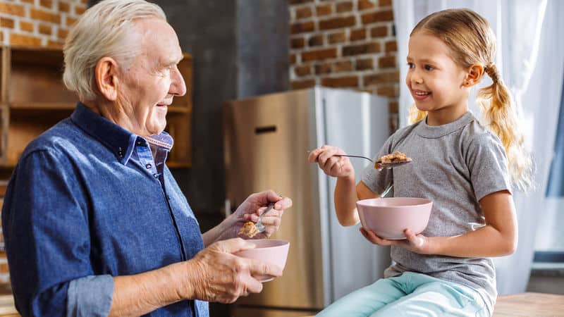 Grandfather eating healthy cereal with his granddaughter Image