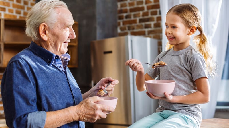 Grandfather eating healthy cereal with his granddaughter