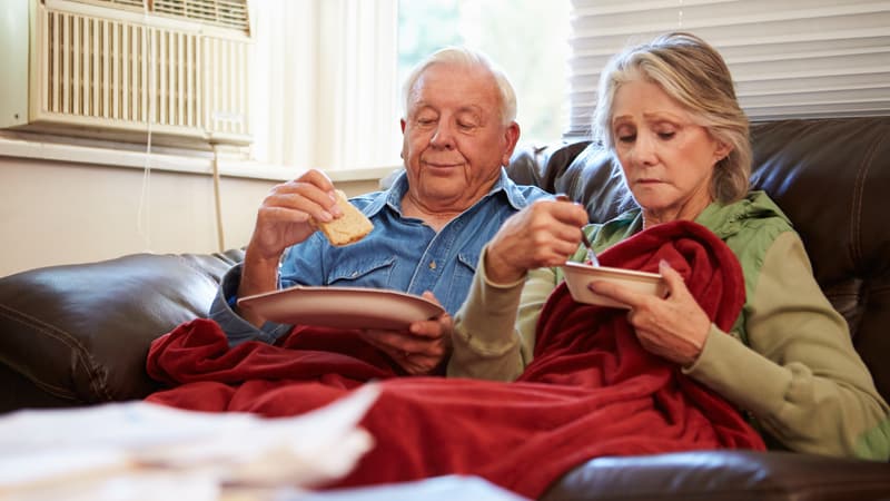 Senior couple stress eating on the couch