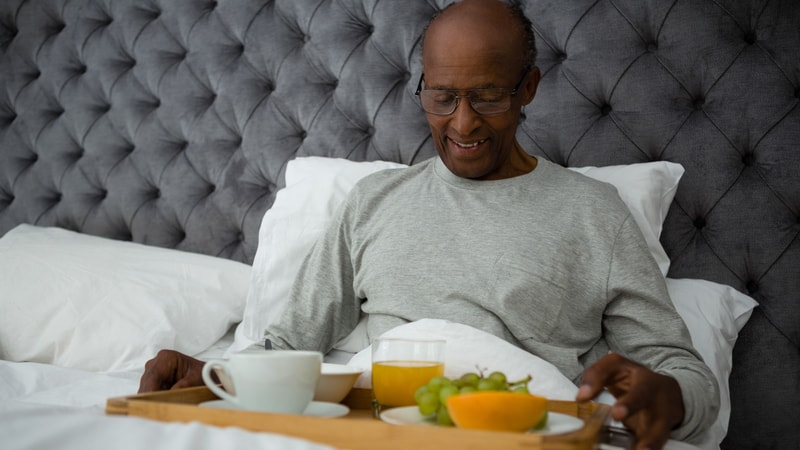 Senior man eating breakfast in bed