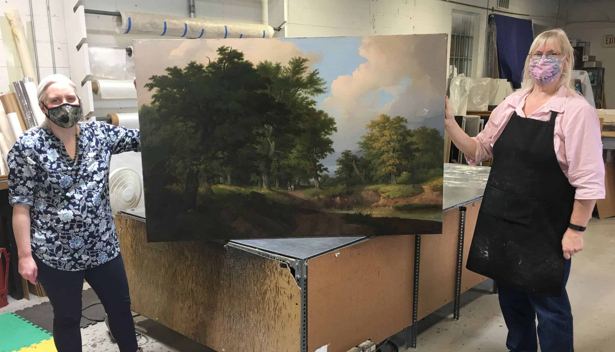 Art conservators Lorraine Brevig and Beth Fulton with an early American landscape in the process of being conserved