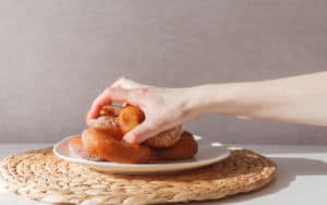 Hand grabbing a plate of donuts for a sugar binge Image