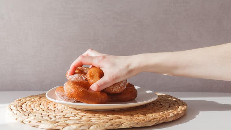 Hand grabbing a plate of donuts for a sugar binge Image