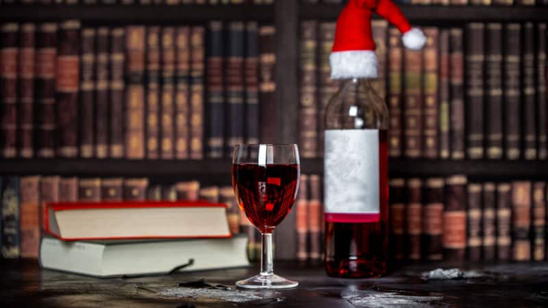 Books in a library, wine, and Christmas hat Image