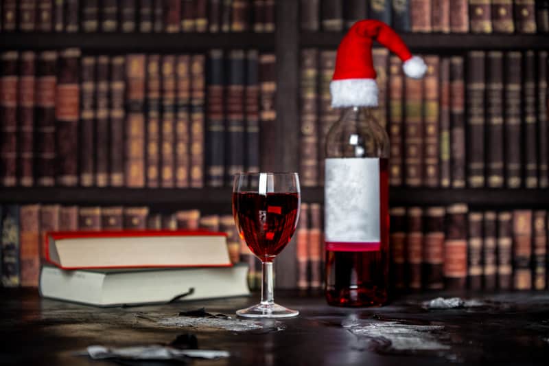 Books in a library, wine, and Christmas hat