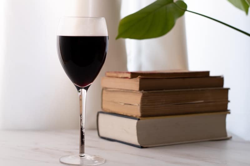 A glass of red wine and classic books