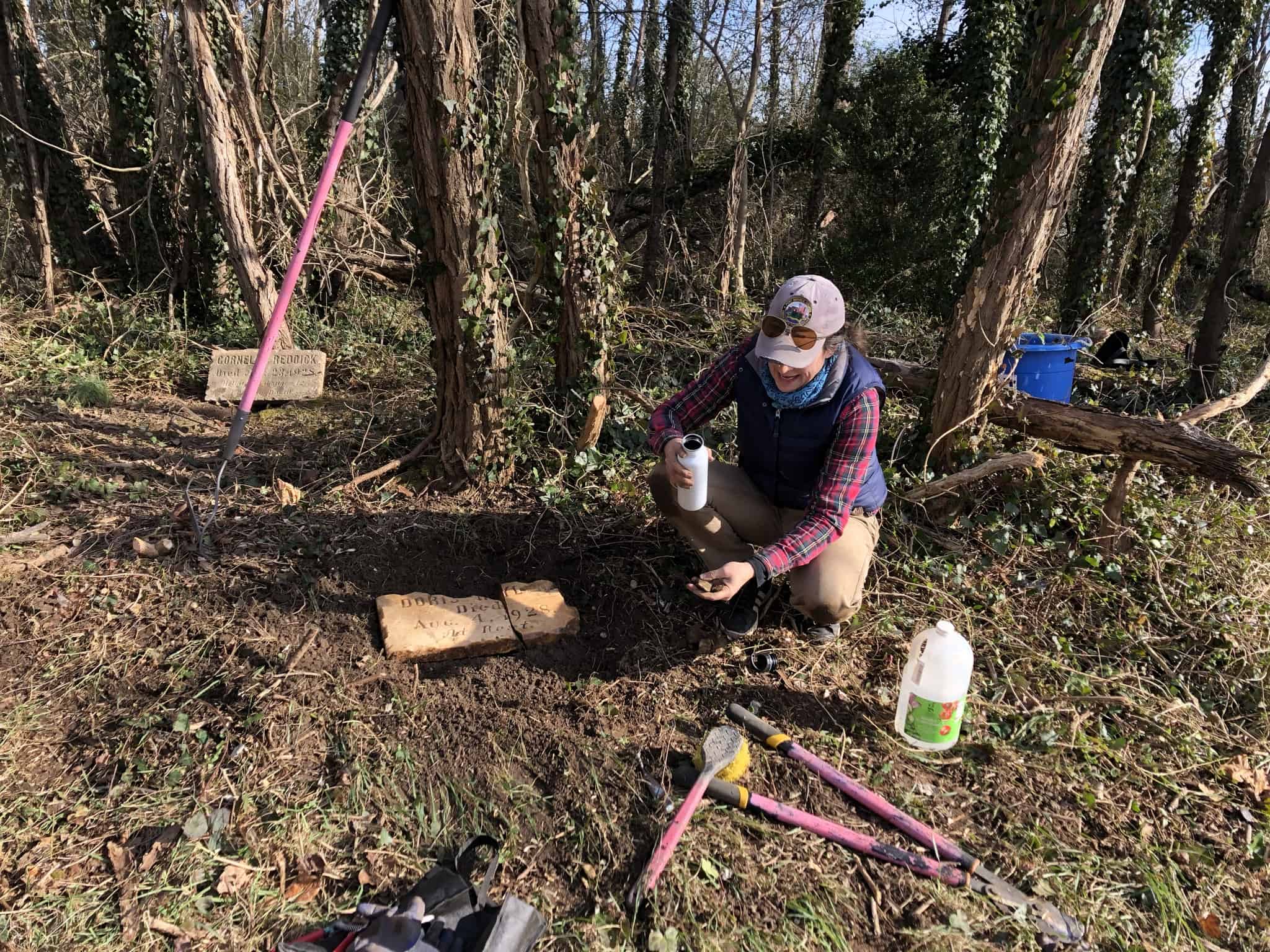 Volunteer tending a gravesite at Woodland Cemetery, a historic African American cemetery in Richmond, Virginia