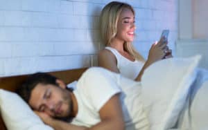 Wife on the phone in bed exhibiting risky behavior Image