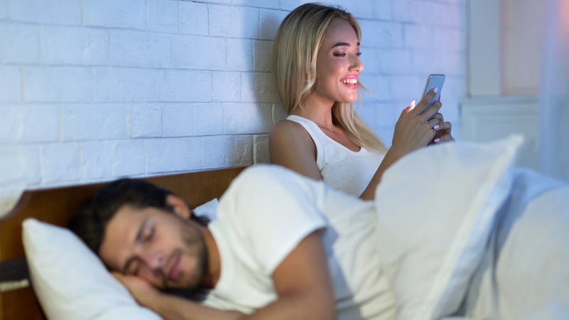 Wife on the phone in bed exhibiting risky behavior