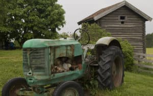 Old tractor in front of barn on a field for essay on childhood memories stir the heart Image