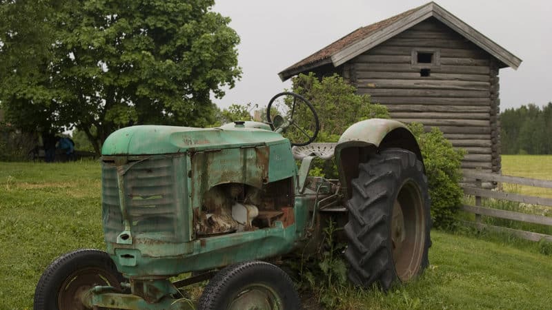 Old tractor in front of barn on a field for essay on childhood memories stir the heart Image
