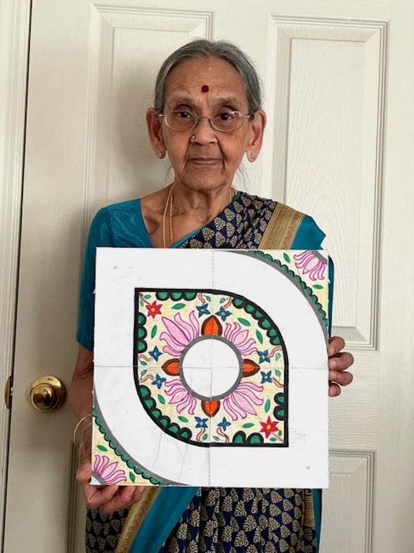 Older Indian woman in traditional sari with kolam