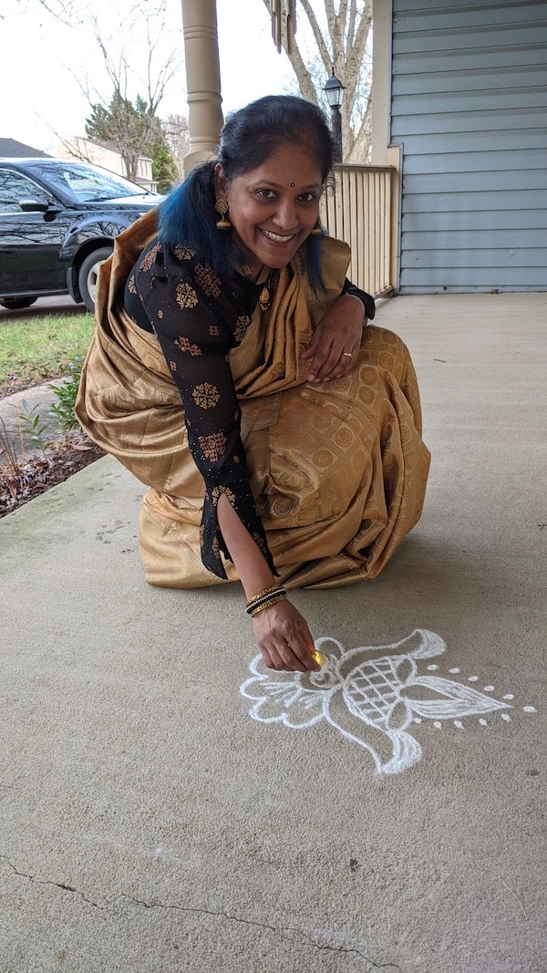 Indian woman drawing kolam in front of house