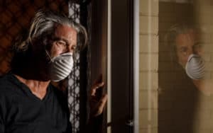 COVID mental health repercussions as man in mask peers sadly out the window. A picture of pandemic stress Image