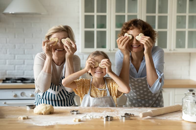 Multigenerational family at home, Grandmom, granddaughter, and mom in the kitchen making cookies. For “Moving Aging Parents into Your Home, Part 1.” Photo credit: Fizkes, Dreamstime