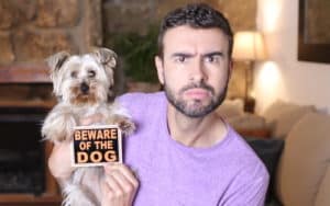 Man holding small dog and Beware of the Dog sign. For article on 