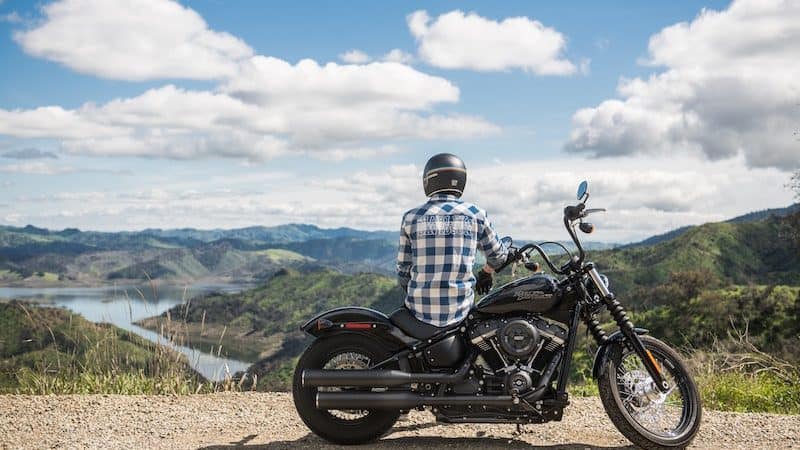 Motorcyclist sitting on motorcycle looking over lake and valley. For 5 Motorcycle Road Trip Tips Image