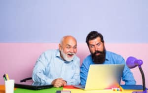 older man and younger man looking in astonishment at a laptop. For baby boomer social media strategy Image
