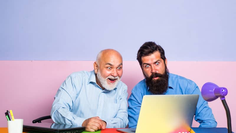 older man and younger man looking in astonishment at a laptop. For baby boomer social media strategy Image