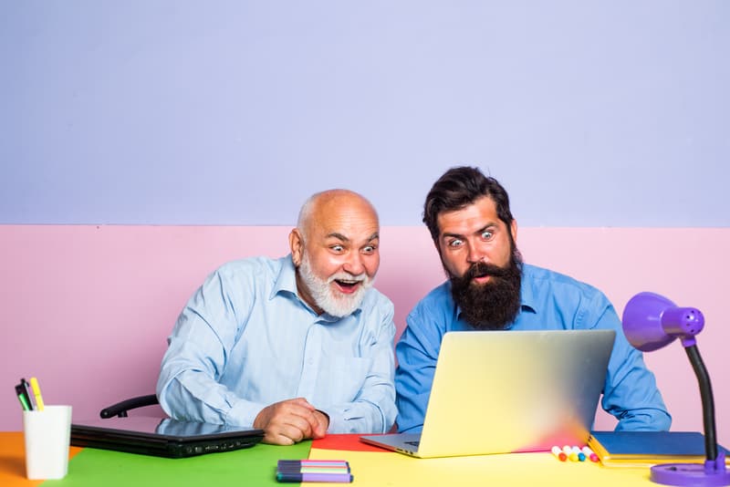 older man and younger man looking in astonishment at a laptop. For baby boomer social media strategy