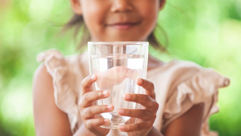 Little girl with a glass of water practicing hydration