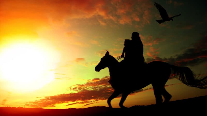 Father and daughter on a horse, silhouetted against the setting sun. For Farmer and father fights COVID Image