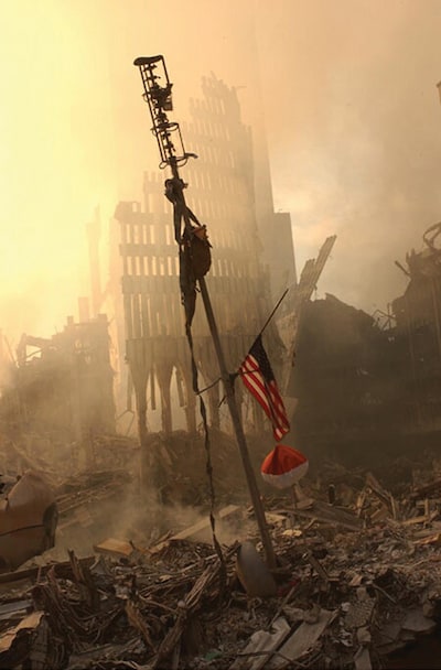 394479 11: A US flag flies from a television antenna September 13, 2001 amid the rubble of the World Trade Center after an aircraft crashed into it September 11 as part of a terrorist attack. The antenna was once at the top of one of the 110 story twin towers. (Photo by FEMA/Getty Images)