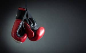 Red boxing gloves hanging over a black background. Credit Refat Mamutov, Dreamstime. For article, Can Boxing Classes Help with Parkinson’s? Image