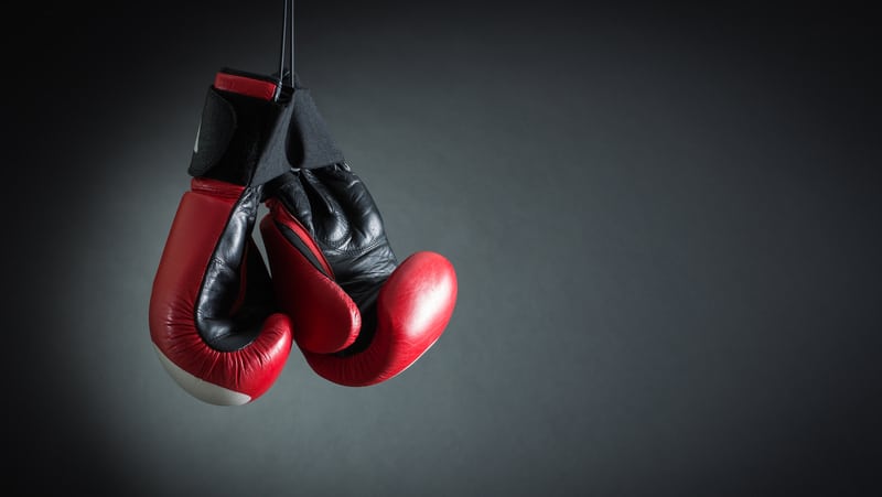 Red boxing gloves hanging over a black background. Credit Refat Mamutov, Dreamstime. For article, Can Boxing Classes Help with Parkinson’s?