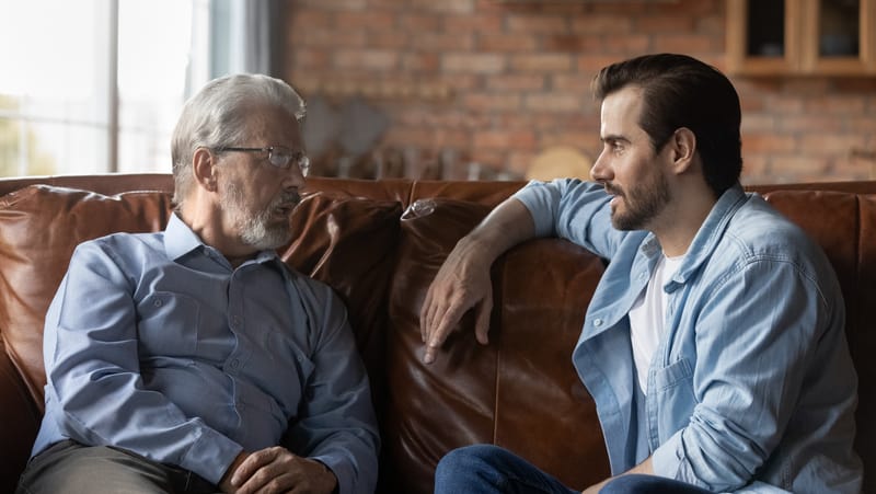 father and son talking at home. Photo credit, Fizkes Dreamstime. For article on A Parkinson’s Disease Caregiver Story