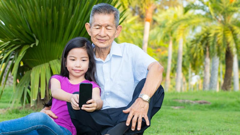 Reflections on Aging and Life - grandfather and granddaughter in parking looking at smartphone Image