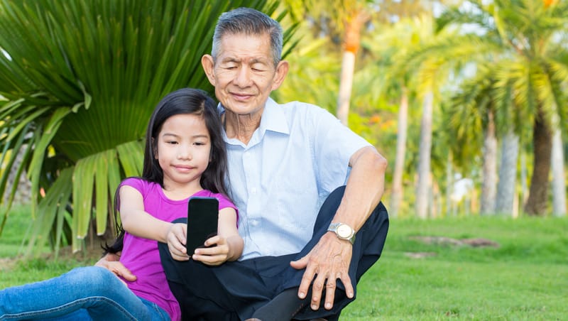 Reflections on Aging and Life - grandfather and granddaughter in parking looking at smartphone