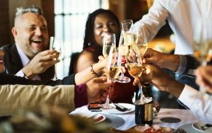 People celebrating with Champagne at a dinner party. Photo Rawpixelimages Dreamstime. For article on Taking Leftover Containers to a Dinner Party Image