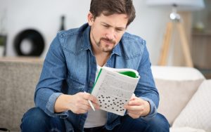 Man doing puzzle, sitting on a sofa Image