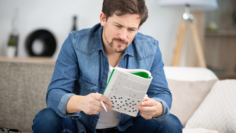 Man doing puzzle, sitting on a sofa