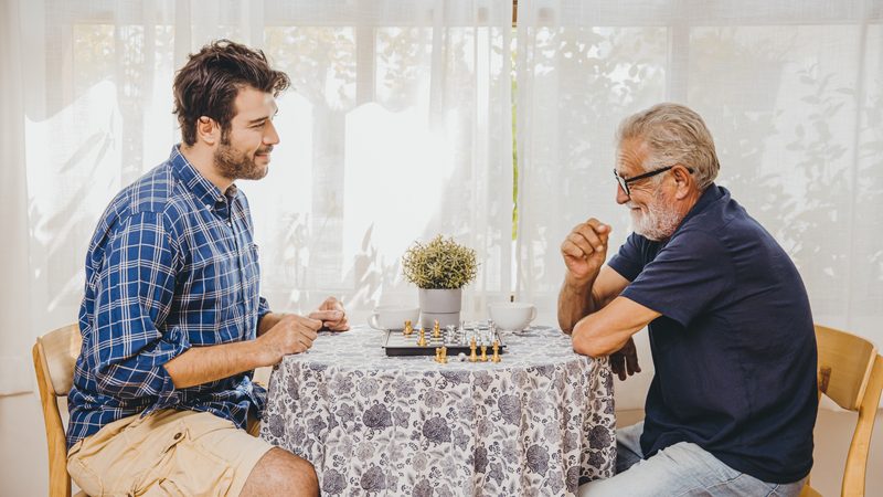 Two men playing chess at a kitchen table Photo Korn Vitthayanukarun Dreamstime. For article on Simple, low-cost, low-tech brain-training activities Image
