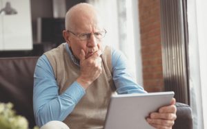 confused man holding a tablet Photo Piotr Adamowicz Dreamstime. For article: Advice from Amy - older man baffled by dating Image